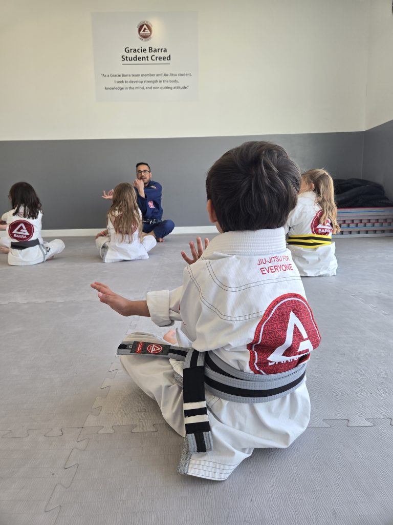 Gracie Barra student following instructions performing a stretch.